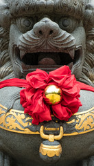 Stone lion and red ribbon at Chinese shrine detail view
