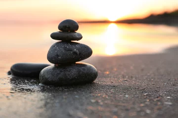 Foto auf Acrylglas Dunkle Steine auf Sand am Meer bei Sonnenuntergang, Platz für Text. Zen-Konzept © New Africa