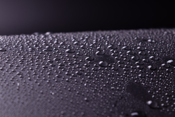 small chaotic transparent drops on a black background with white highlights from light and inhomogeneous in size.