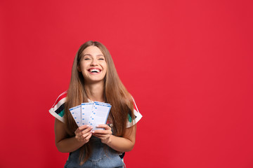 Portrait of happy young woman with lottery tickets on red background