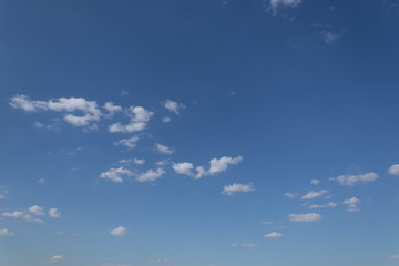 White fluffy clouds on a distant blue sky over a field in sunny weather with a garrison.