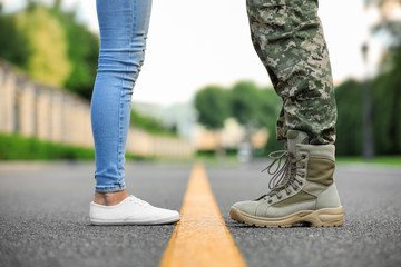 Man in military uniform and young woman separated by yellow line on road, closeup