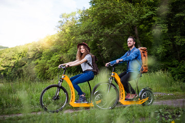 Young tourist couple travellers with electric scooters in nature.