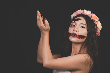 A female ghost or a zombie wearing a white dress with a bloody knife in his left hand on a black, horror background. Black and white Halloween concept.