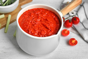 Delicious tomato sauce in pan on white wooden table, closeup