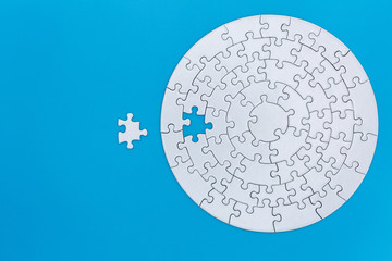 Unfinished white jigsaw puzzle pieces on blue background, The last jigsaw puzzle of success. - obrazy, fototapety, plakaty