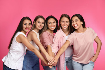 Happy women putting hands together on pink background. Girl power concept