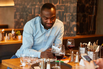 Afrikanischer Mann schreibt eine SMS im Restaurant