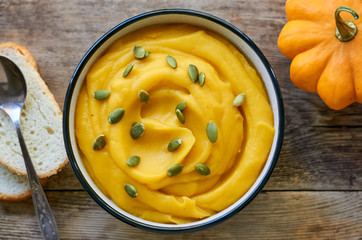 Thick pumpkin cream soup with seeds on a wooden background    