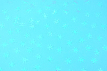 Holographic foil snowflakes confetti sparse on trendy blue background. Simple holiday concept. Winter festive backdrop. Top view, flat lay