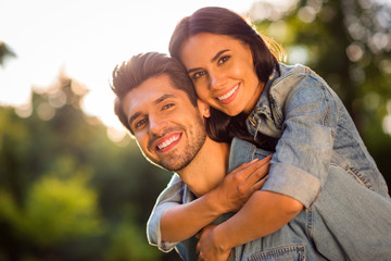 Close up photo of charming spouses having brunet hair cuddling piggyback outside in forest