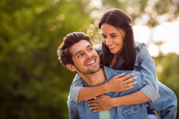 Obraz premium Close up photo of lovely sweethearts looking piggyback wearing denim jeans jackets outdoors