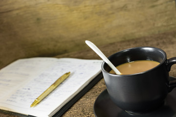 Cup of coffee and opened book on old wood background