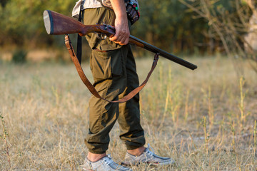 Hunting period, autumn season open. A hunter with a gun in his hands in hunting clothes in the...