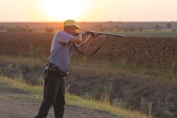 Hunting period, autumn season open. A hunter with a gun in his hands in hunting clothes in the...