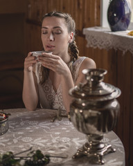 Russian woman near the table with samovar. Traditional tea time. Retro style photo