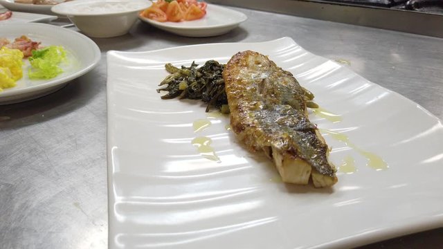 Pesce spigola fresca su un piatto con verdura
