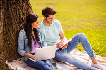 Her she his he attractive lovely charming cheerful cheery married spouses studying preparing homework task writing exercise sitting on veil cover grass springtime outside