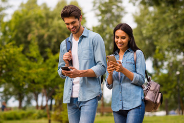 Obraz premium Photo of funny pair using telephones while walking green park wear casual denim outfit