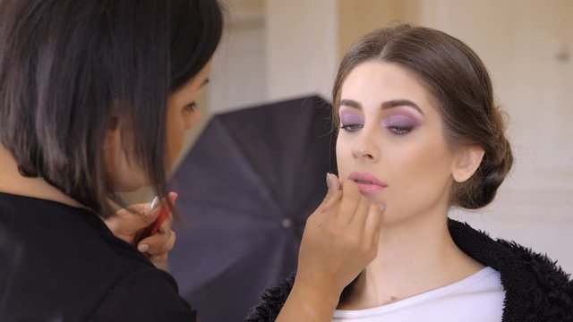 Makeup Artist Applying Lip Gloss On Lips beautiful  Model