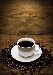 Coffee beans and cup on old wooden background