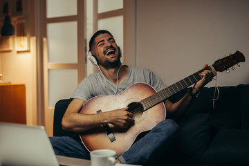 man playing guitar at his home. evening scene