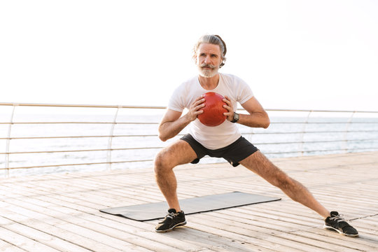 Image Of Gray-haired Old Man Doing Exercise With Medicine Ball