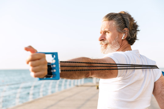 Image of handsome elderly man doing exercise with expander