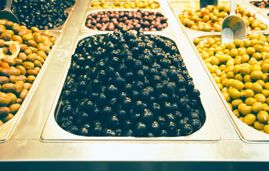 Olives in bowls at the market for sale. Traditional mediterranean food suitable for vegans and vegetarians.