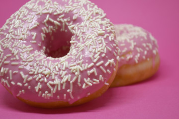 Donuts with icing on pastel pink background. Sweet donuts.