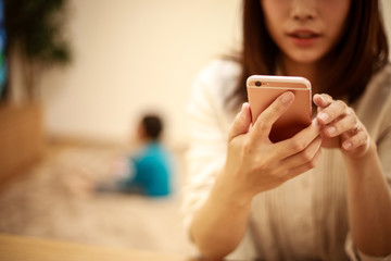スマートフォンの操作に夢中になる母親