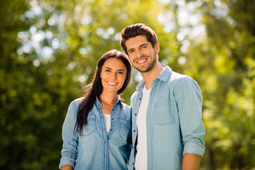 Photo of overjoyed pair standing together in green summer park wear denim outfit