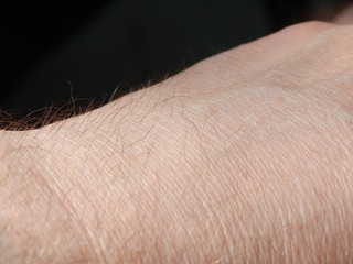 Male back of the hand with closeup of skin and tiny hair, black background