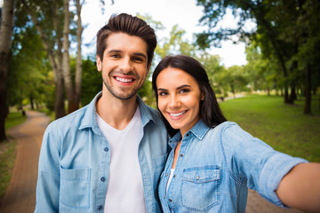 Close up photo of cheerful married couple making photo smiling wearing denim jeans shirt outside in forest