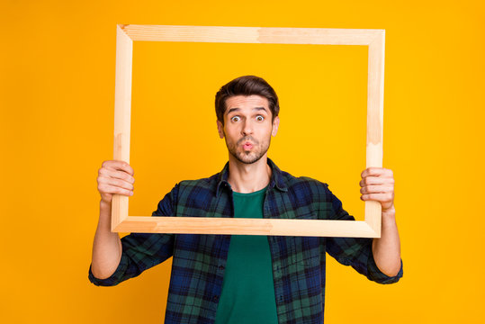 Photo Of Funny Guy Holding Wooden Picture Frame Looking Through It Sending Air Kiss Wear Casual Plaid Shirt Isolated Yellow Color Background