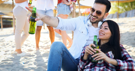 Happy young couple drinking beer and having fun at the beach