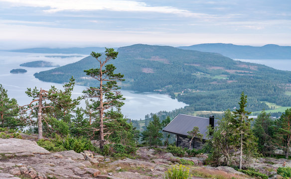 Public tourist rest house in front of view over Scandinavian mountains with pine tree forest, the village and two sea bays, summer day with heavy dramatic clouds, North Sweden