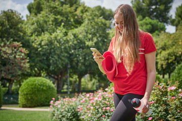 sporty girl in the park looking at the smartphone