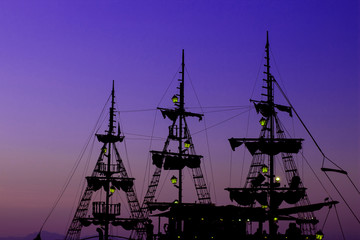 romantic vacation cruise ship wooden medieval mast dark silhouette and gas lamps illumination on blue and purple sunset evening sky background copy space for text