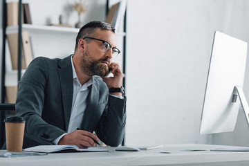 handsome businessman in formal wear talking on smartphone and holding pen