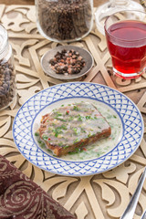 Jellied meat on a plate and glass of red drink on oriental wooden table