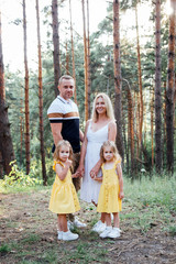 Mother and father outdoors with twin daughters, full-length 