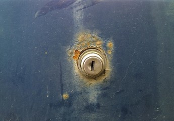 Lock on dirty rusty trunk lid of old car. Sheet metal corrosion.  Dirty defect surface, background...
