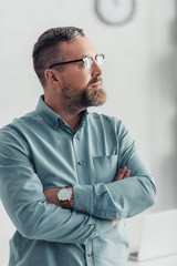 handsome businessman in shirt and glasses looking away in office