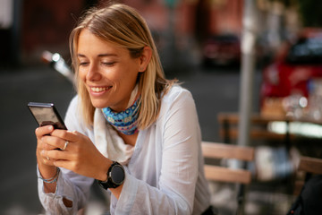 Young businesswoman using phone in cafe