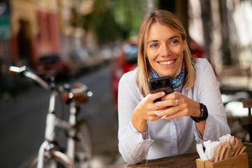 Young businesswoman using phone in cafe