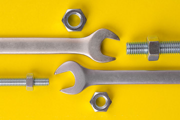 Wrench and bolt with nuts. Wrench and nuts with bolts. Wrench and nuts with bolts on a yellow...