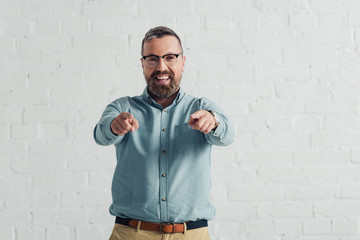 handsome and smiling businessman in shirt pointing with finger