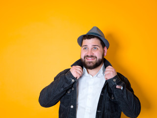 cool man with hat and black beard is posing in front of yellow, orange background