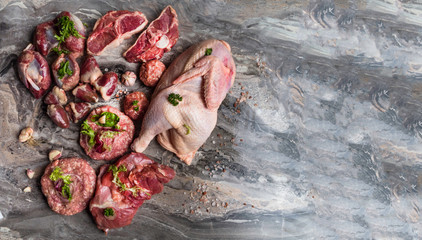 Fresh raw meat. Different types of raw pork meat, chicken, beef, turkey giblets with herbs on dark marble, copy space
